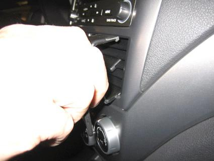 En hand som använder ett verktyg för att justera bilens luftutlopp.