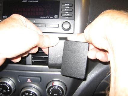 Händer installerar en del i instrumentpanelen på en Subaru Forester/Impreza.