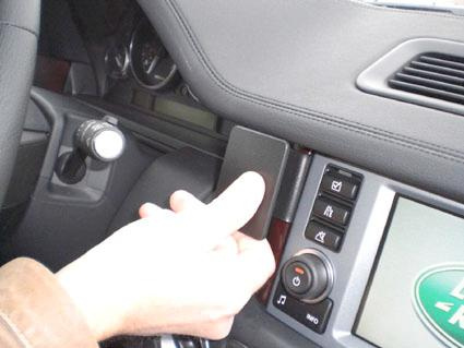 En hand interagerar med en panel i en bils mittkonsol.