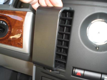 Del av bilens instrumentpanel med en ventil och ett förvaringsfack.