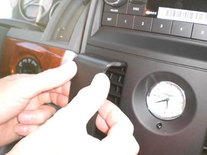 En person installerar något på instrumentpanelen i en Chrysler Voyager.