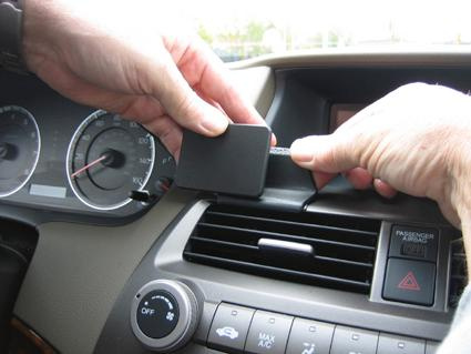 En hand installerar en enhet i en Honda Accord 08-08.