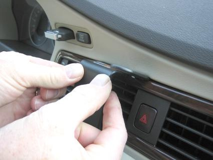 En person tar bort en del av träpanelen i en Volvo bilinteriör.