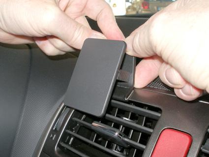 En person fäster en enhet på luftventilen i en bil.