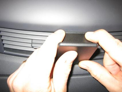 En person håller i en svart plastdetalj nära en bilventil.