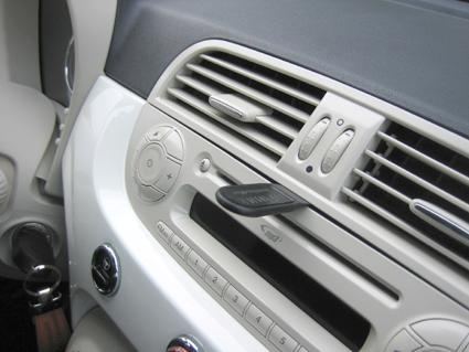 Interiör av Fiat 500 med radio, luftventiler och knappar.