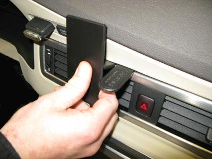 Man håller i en svart panel som verkar passa i bilens mittkonsol.