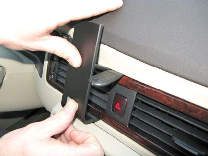 En person installerar en svart plastdel på bilens instrumentpanel.