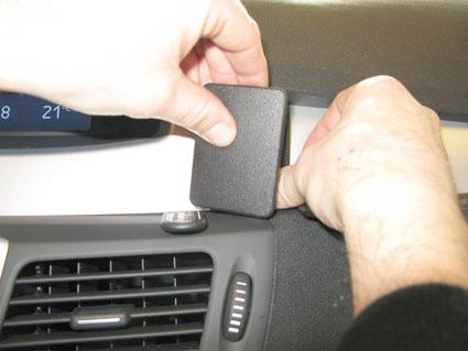 En hand placerar en svart platta på instrumentpanelen i en bil.
