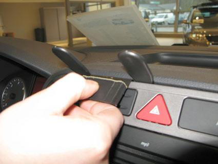 En hand trycker på en knapp i en bil, med instrumentbräda i förgrunden.