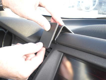 En person fäster en svart platta på en bils instrumentbräda.