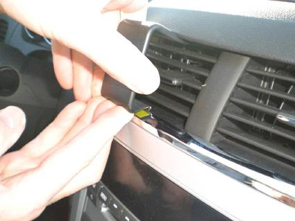 En hand som placerar en del på en bils ventilationsgaller.