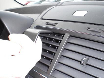 En hand installeras en monteringsbygel i en bilventilationsgaller.