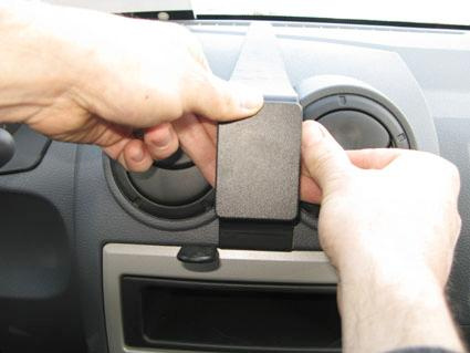 En person fäster en del på instrumentbrädan i en Dacia Logan.