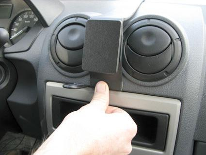En hand monterar en centralt placerad enhet på instrumentpanelen i en Dacia Logan.