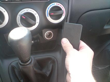 En hand som håller en svart enhet vid växelspaken i en bil.