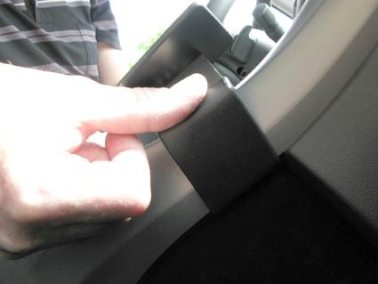 En hand pekar på en del av en bilinteriör.