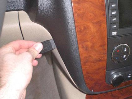 En hand drar i en svart rem vid instrumentpanelen i en Chevrolet Avalanche.
