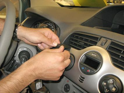 En person installerar en del på instrumentpanelen i en Renault Kangoo.