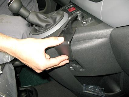 En hand justerar en del av bilens inredning, troligen armstöd eller kontroller.