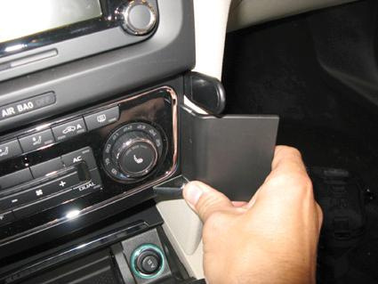En hand öppnar en panel vid bilens instrumentbräda.