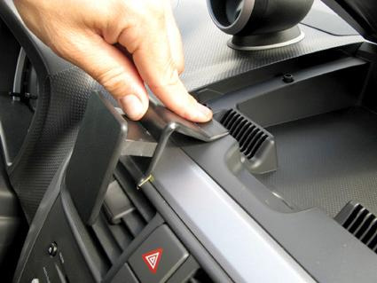 En hand placerar en monteringsbygel på en bils instrumentpanel.