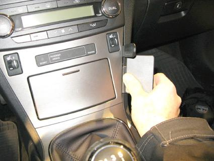 En hand håller i en enhet på bilens mittkonsol.