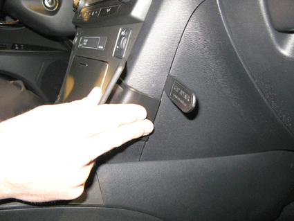 Hand trycker på en knapp på instrumentpanelen i en Toyota Avensis.