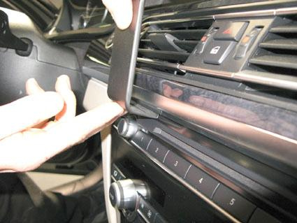 En hand visar hur man tar bort en panel i BMW 730-750 F01, F02.