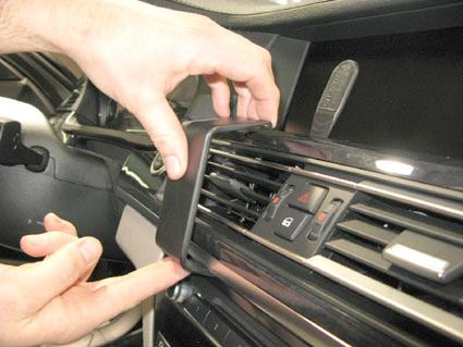 En person avlägsnar en del av instrumentpanelen i en BMW 7-serie.