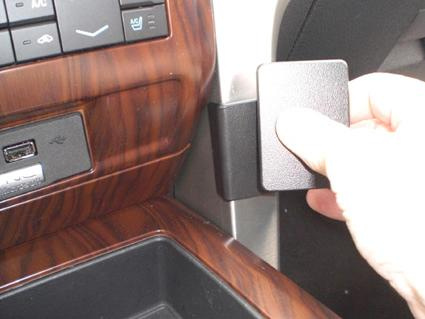 En hand som trycker på en knapp i en bilinteriör nära växelspaken.