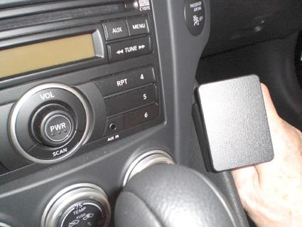 En interiör av en bil med ljudsystem och en hand som håller en svart komponent.