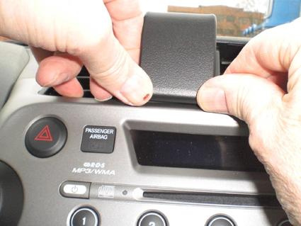 En person fäster en komponent på instrumentbrädan i en Honda Fit/Jazz.