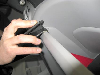 En hand som fäster något på insidan av en bil.