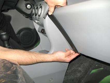 Bilden visar en hand som installerar en del i Nissan Pixo 09-15 interiör.