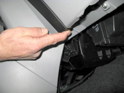 En hand pekar på en del av interiören i en Nissan Pixo 09-15.