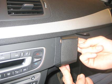 Hand som fäster en plastdetalj på instrumentpanelen i en Renault Mégane.