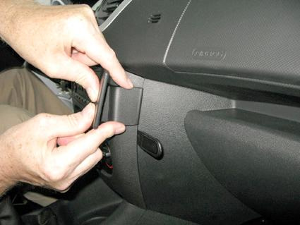 En person installerar en komponent i interiören av en Peugeot 206+.