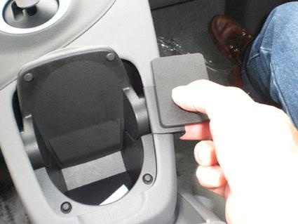 En hand håller en platta över en kopp-hållare i en Toyota Prius.