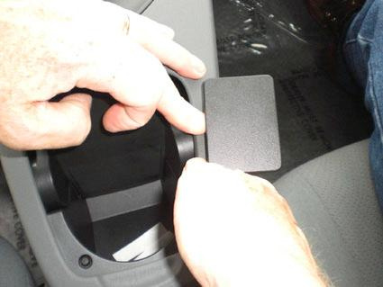 Hand som pekar på en del av interiören i Toyota Prius, troligen en lucka eller fack.