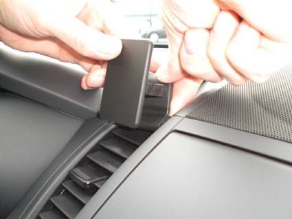 En hand fäster en svart del på en bilinteriör.