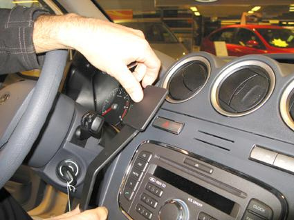 En hand installerar en del på instrumentpanelen i en Ford Transit Connect.