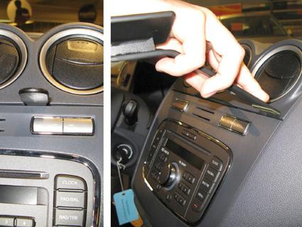 Visar en hand som installerar eller justerar en del i bilens instrumentbräda.