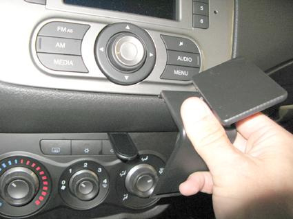 Hand som håller en panelbit från instrumentbrädan i en Alfa Romeo MiTo.