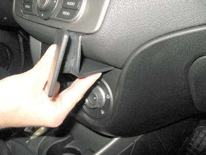 En hand tar ut en liten låda eller fack från bilens interiör.