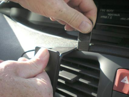 En hand som justerar en del på en bils instrumentbräda.