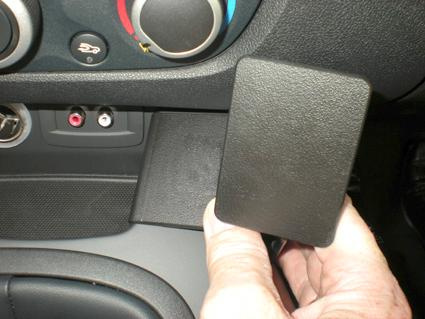 En hand håller i en svart del av bilens interiör, nära kontrollerna.