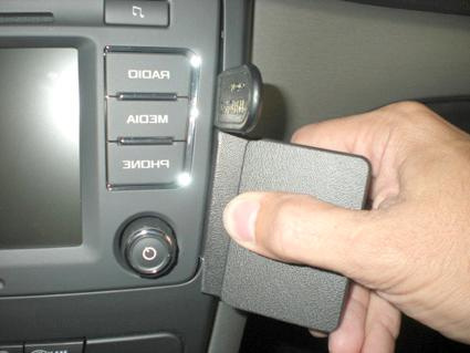 En hand håller en svart hållare i en bils interiör.