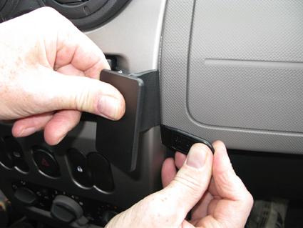 En person installerar en del på instrumentbrädan i en bil.