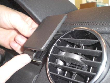 En hand som fäster en svart hållare på en bilventil.